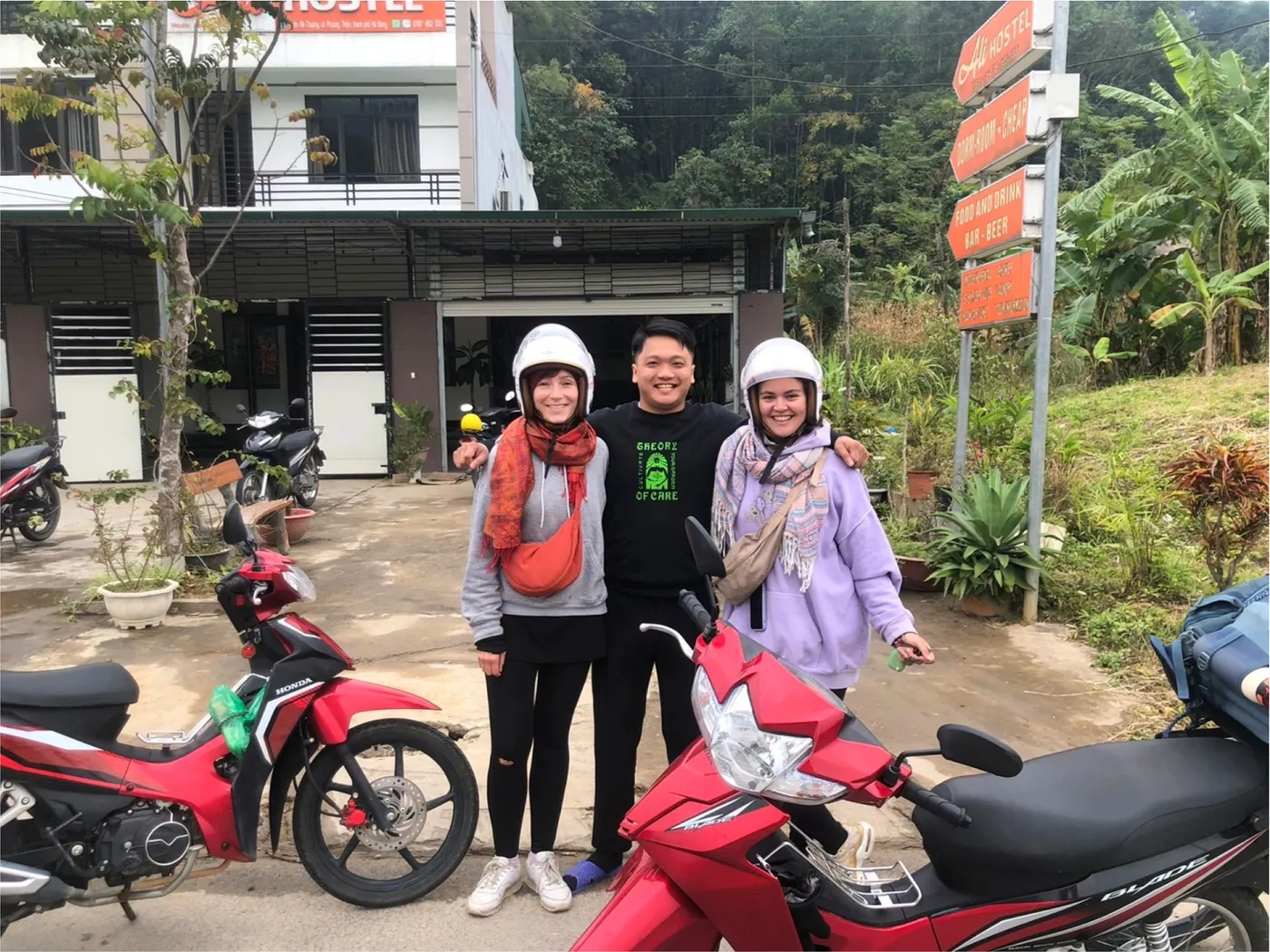 Ali staff with two guests in helmets next to their motorbikes at Ali Hostel