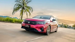 Red Honda City sedan beside a palm tree at sunset