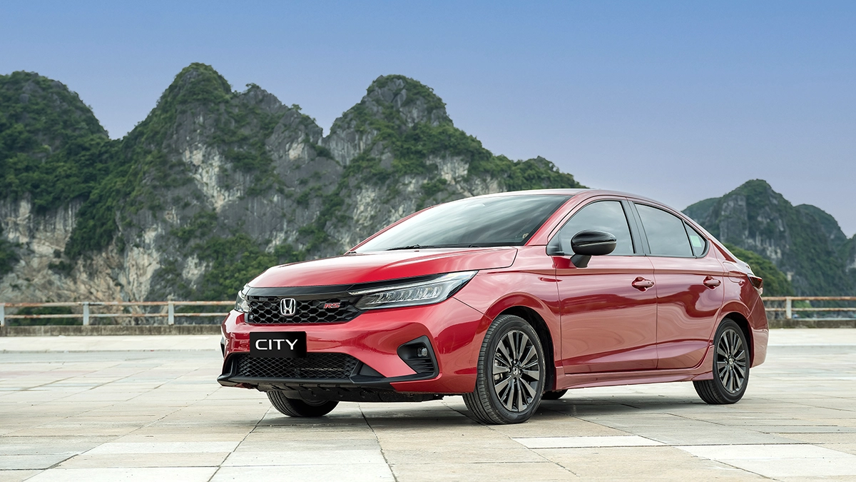 Red Honda City parked on a mountain road below limestone karst peaks in northern Vietnam