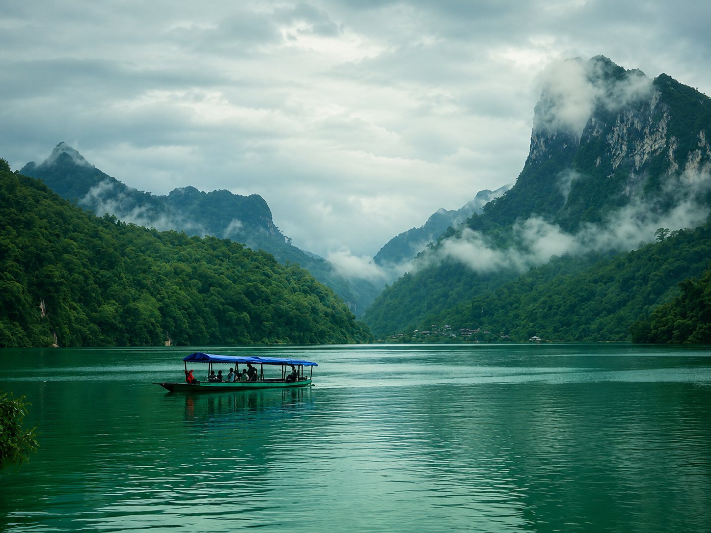 Tour boat crossing Ba Be Lake under misty limestone peaks