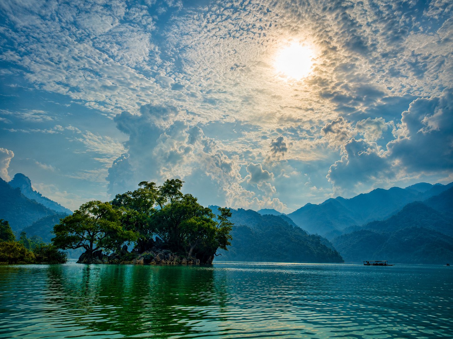 A tree-covered islet on Ba Be Lake in late afternoon light
