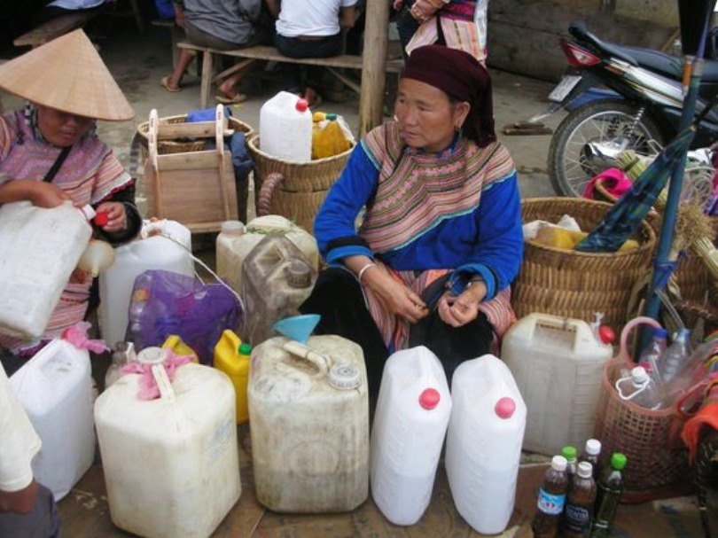 Ha Giang happy water: Hmong women selling homemade corn wine in jerrycans at a highland market