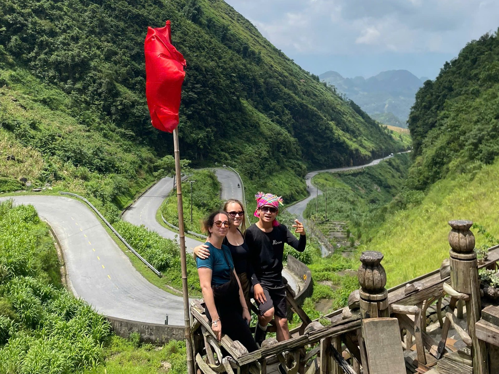 Hairpin road through a deep green valley on the Ha Giang Loop in August, with Ali guests at the viewpoint