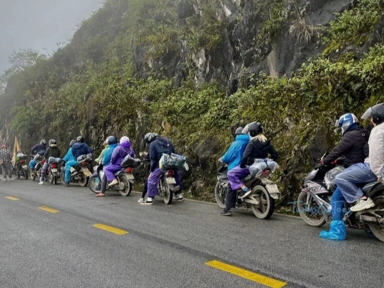 Motorbike group in rain gear on a misty Ma Pi Leng road, Ha Giang Loop in December