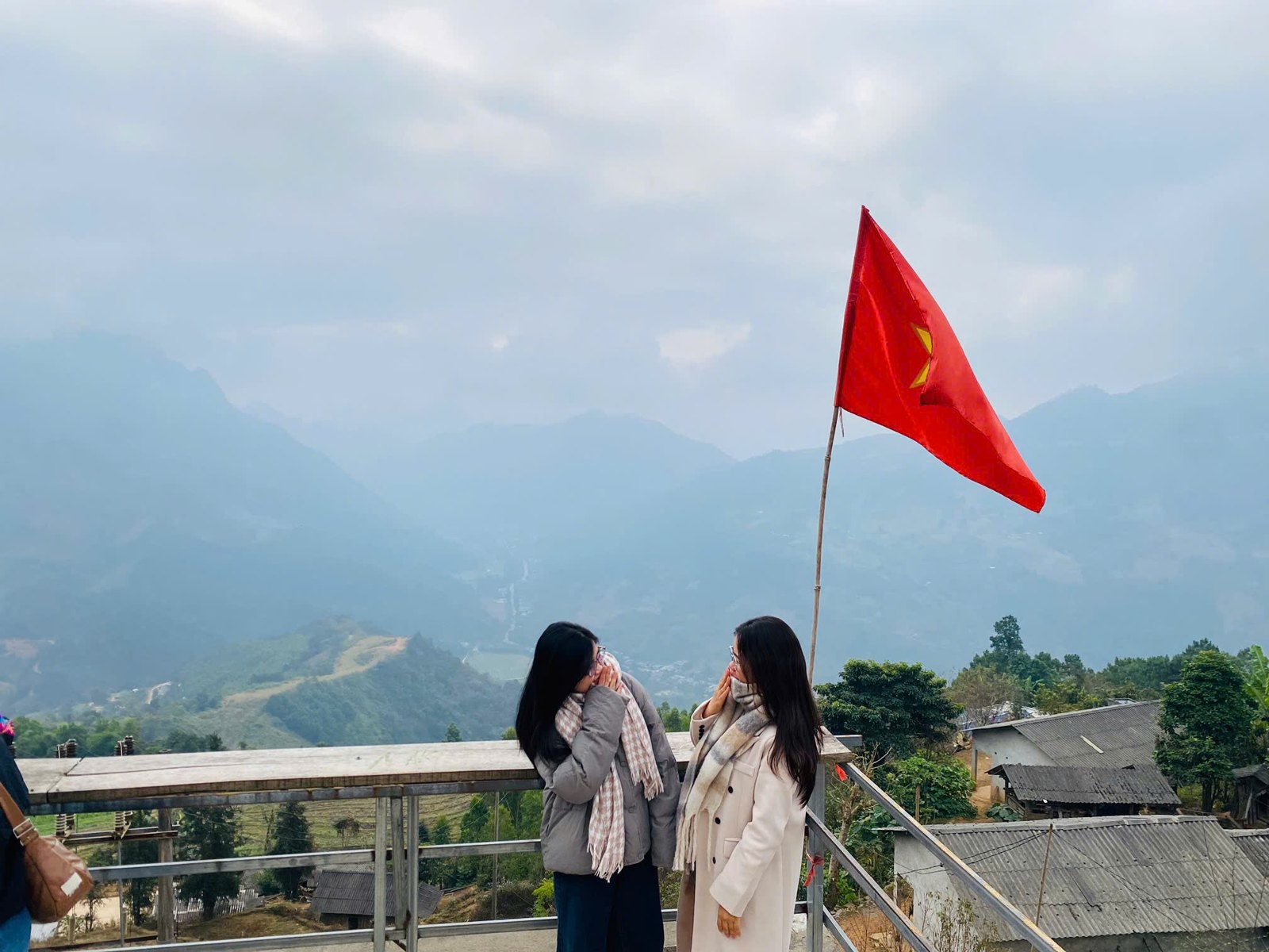 Ha Giang Loop in February: Tet, Blossoms and Drizzle (2027 Guide) 6 Two guests in down jackets at a foggy roadside viewpoint on the Ha Giang Loop in February