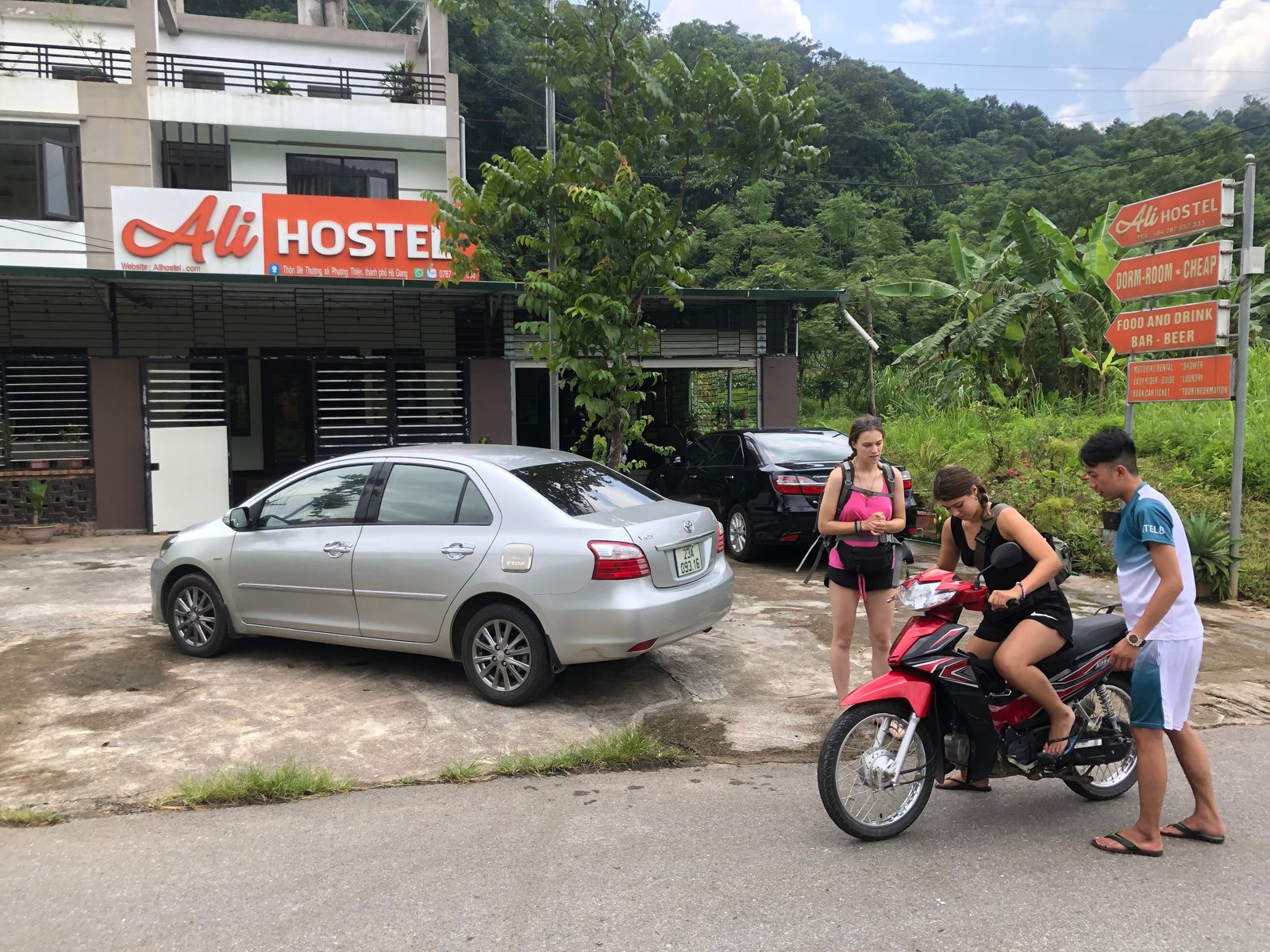 Ha Giang Loop Luggage: Where to Leave Your Big Bag and What to Carry (2026) 3 Two travellers with small day bags on a motorbike outside Ali Hostel, Ha Giang