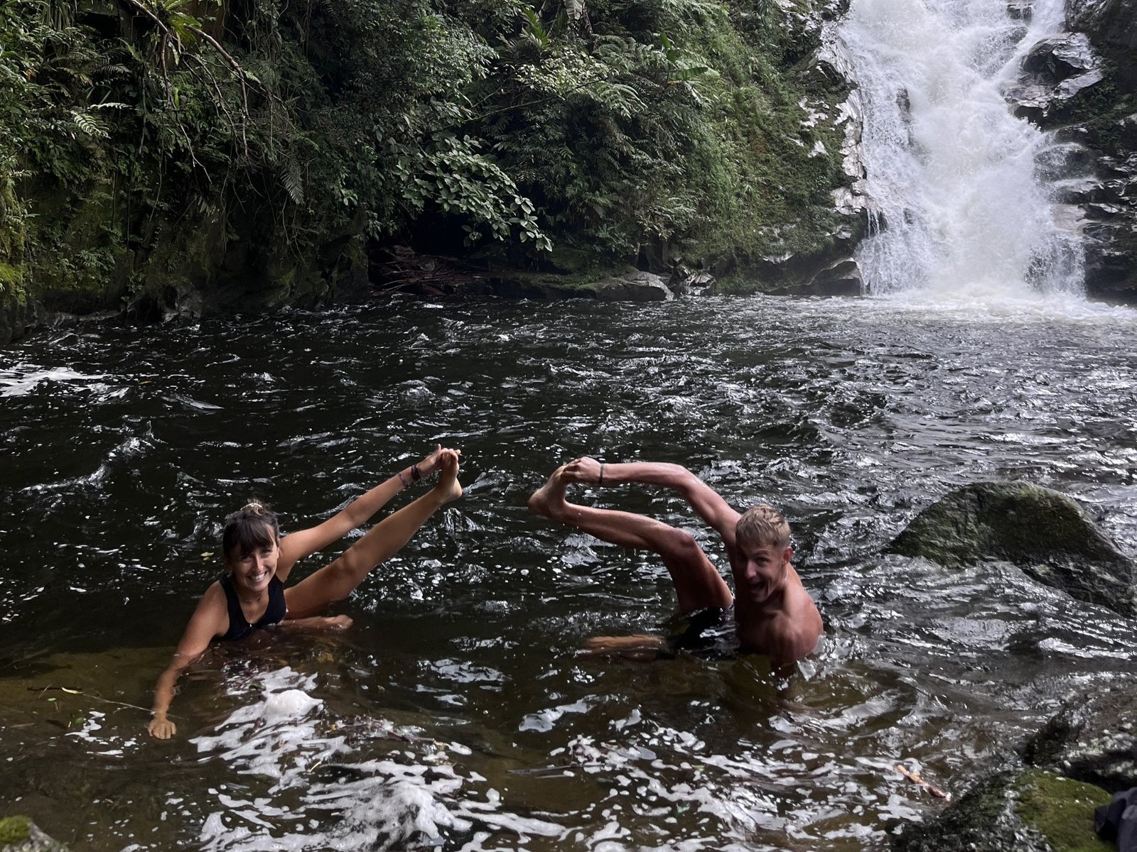 Trekkers swimming under a waterfall on a village trek near Ha Giang