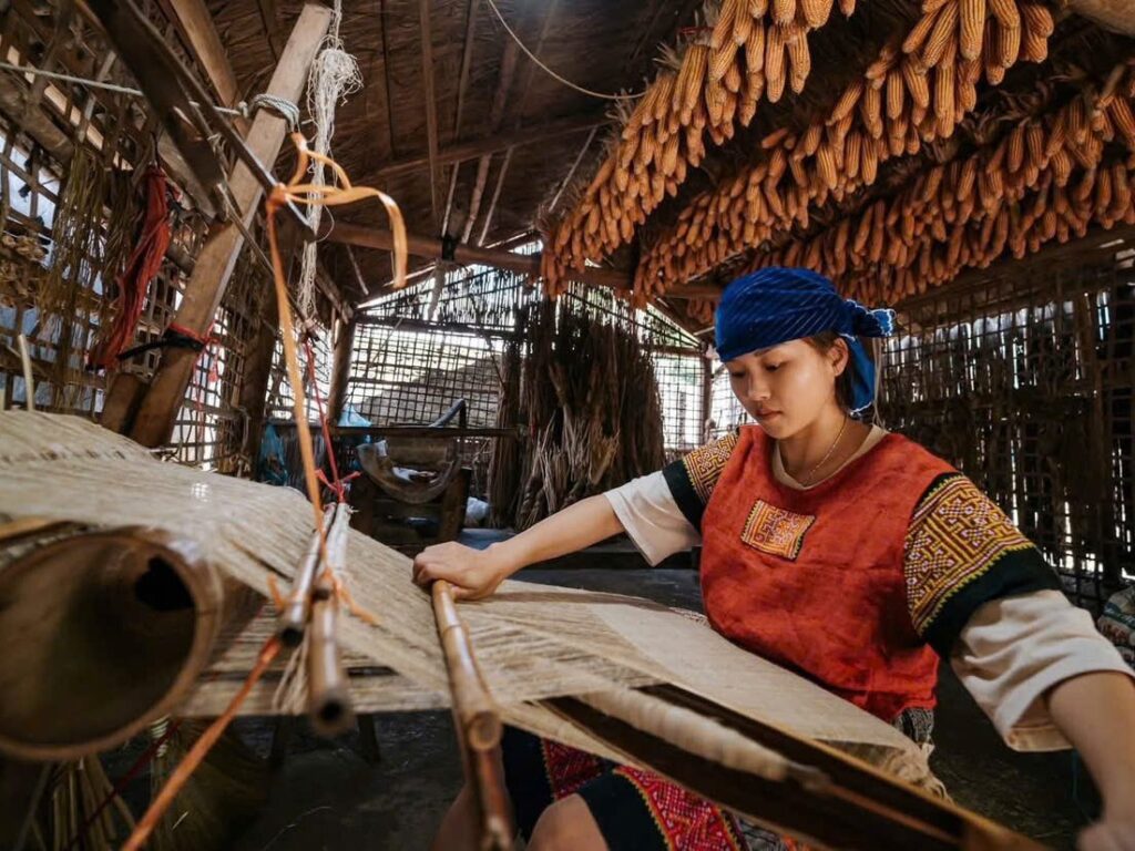Hmong woman weaving hemp cloth on a wooden loom in Lung Tam village, Ha Giang